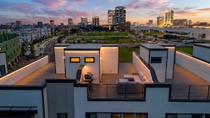 A modern residential building with a rooftop deck, a view of the city skyline, and a river in the background. - Luxury 3BR Waterfront w/ Private Rooftop Skyline Views (Jacksonville)