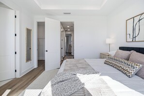 Una camera da letto con un letto grande, un comodino, una lampada e vista su un corridoio.