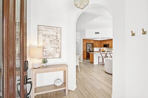 Eine moderne Küche mit Holzschränken, einem Edelstahlkühlschrank und einer weißen Arbeitsplatte.