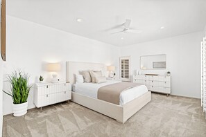 Ein modernes Schlafzimmer mit einem großen Bett, Nachttischen, einem Deckenventilator und einem weißen Kleiderschrank.
