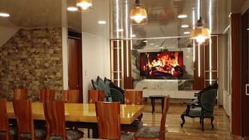 Un espace de restauration moderne avec un mur en pierre, des meubles en bois et des luminaires suspendus.