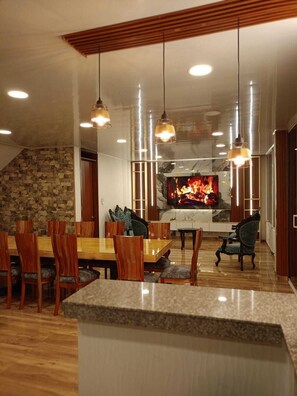 A modern dining area with a stone wall, wooden furniture, and pendant lighting.