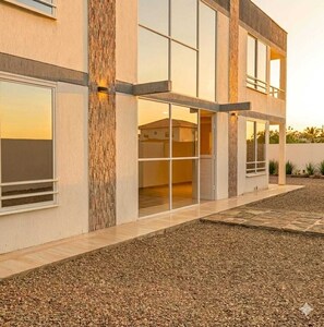 A modern building with a flat roof, large windows, and a gravel driveway.