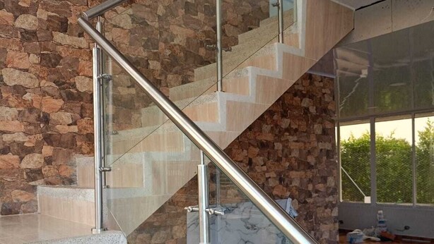 A modern staircase with glass railings and stone walls.