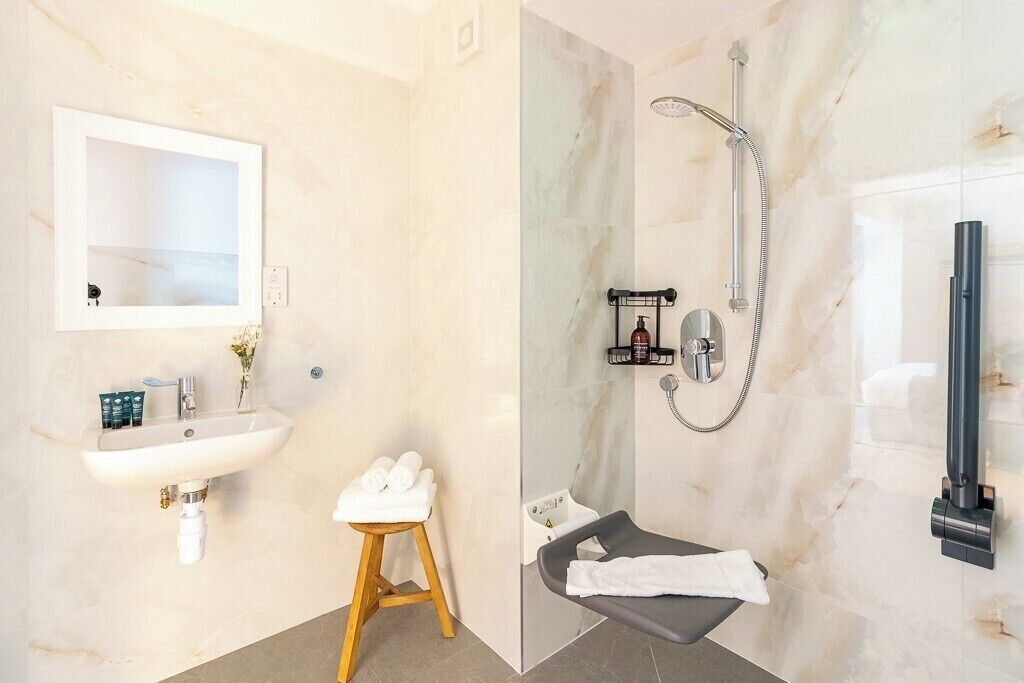 Ein Badezimmer mit Waschbecken, Spiegel, Handtuchhalter und Dusche.