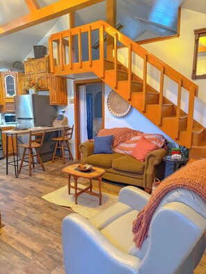A cozy living room with a staircase, wooden furniture, a dining area, and a kitchen. - New Cabin in lake toxaway near gorges state park (Lake Toxaway)