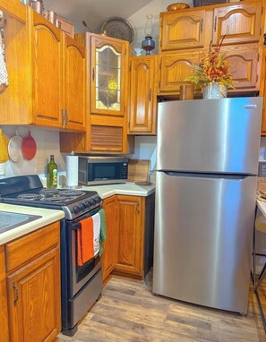 A kitchen with wooden cabinets, a stainless steel refrigerator, a microwave, and a stove. - New Cabin in lake toxaway near gorges state park (Lake Toxaway)