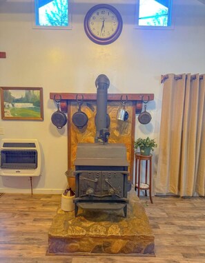 A room with a stone fireplace, a clock, and a painting on the wall. - New Cabin in lake toxaway near gorges state park (Lake Toxaway)