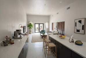 A modern kitchen with a central island, bar stools, a coffee machine, and a dining area with a sofa and chairs. - Modern & Roomy 4BR/3.5BA Gateway to Port of Spain Fully Air-Conditioned (Morvant)