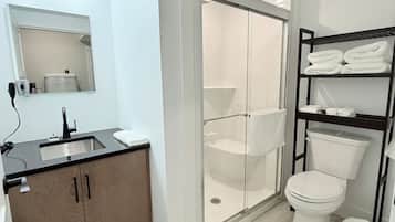 Ein modernes Badezimmer mit Duschkabine aus Glas, Toilette und Waschbecken mit Holzschrank.