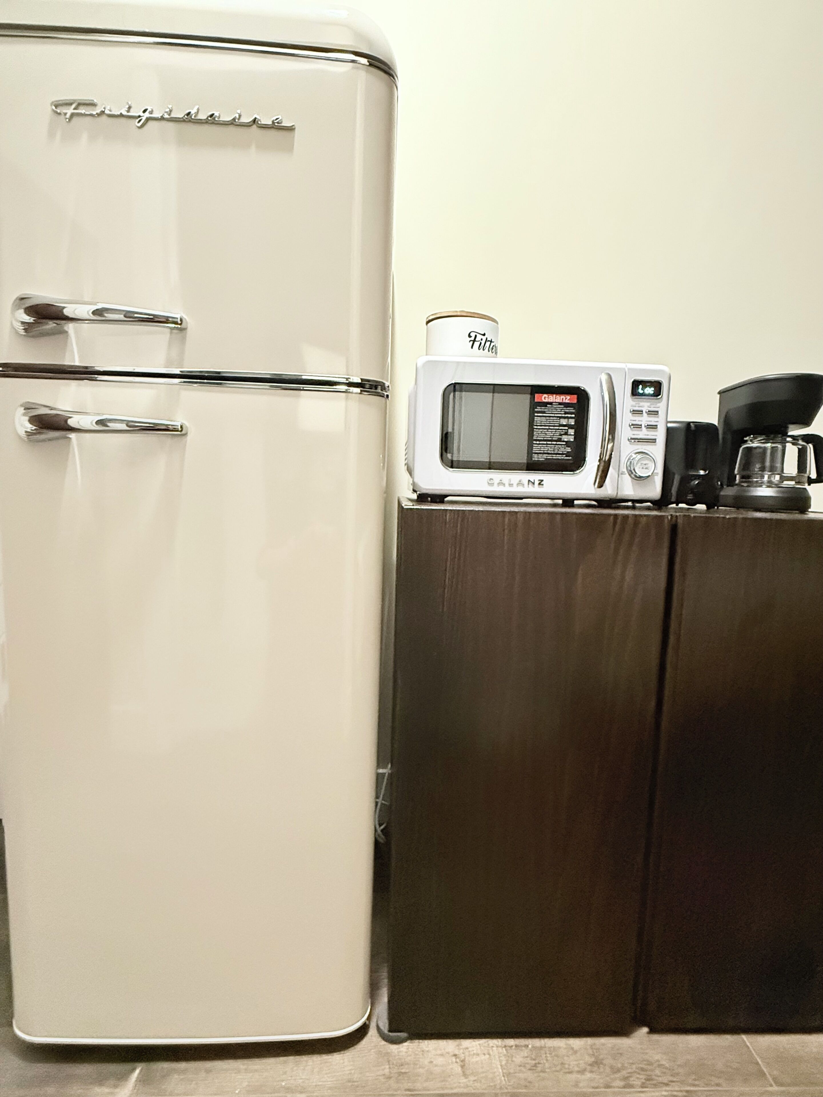 A kitchen with a white refrigerator, a microwave, and a coffee maker on a wooden counter.