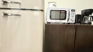 A kitchen with a white refrigerator, a microwave, and a coffee maker on a wooden counter.