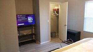 Ein Hotelzimmer mit einem Bett, einem Fernseher auf einem Schrank, einem Kleiderschrank und einem Fenster.
