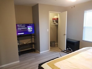 A hotel room with a bed, a TV on a stand, a closet, and a window. - The "Merlot" - Updated Condo - DISCOUNT 4+ nights! (Branson)