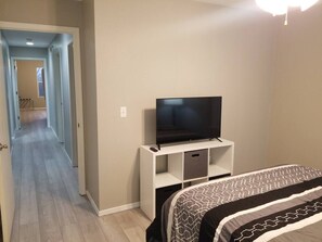 A bedroom with a bed, a TV on a stand, and a hallway leading to another room. - The Merlot at The Vinyards: View, Pool, and Fun! (Branson)