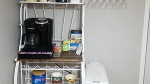 Eine Küchenzeile mit Kaffeemaschine, Gläsern, einer Weinflasche und einem Weinregal.