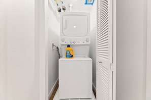 A compact laundry room with a washing machine and a detergent bottle.