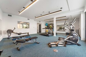 A gym with cardio machines, a bench, and a mirrored wall.
