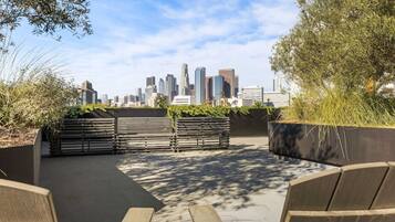 An outdoor seating area with benches and planters, overlooking a city skyline.