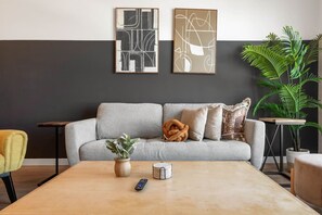 A living room with a grey sofa, a coffee table, a remote control, and two framed abstract artworks on the wall. - Artsy & Chic | Walk to Little Tokyo | DTLA Views (Los Angeles)