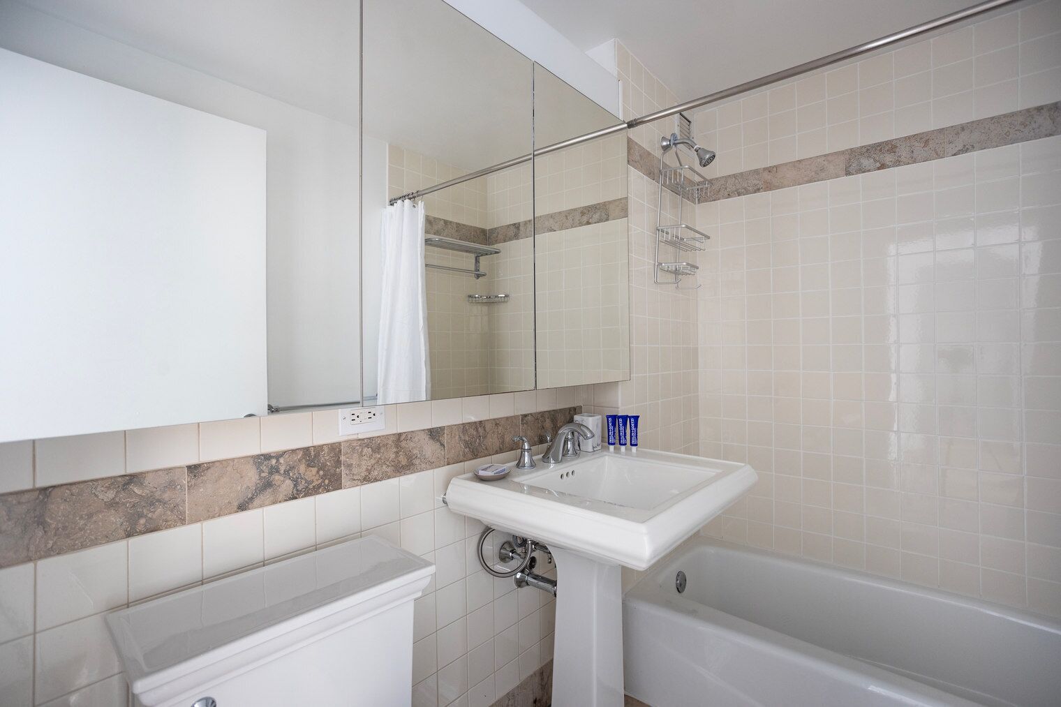 Ein Badezimmer mit weißem Waschbecken, einem Spiegel, einer Dusche und einer Badewanne.