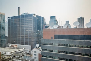 A cityscape with modern buildings, including a prominent glass skyscraper with a BMW logo. - Blueground | Hell's Kitchen, fitness center, nr Central Park (New York)