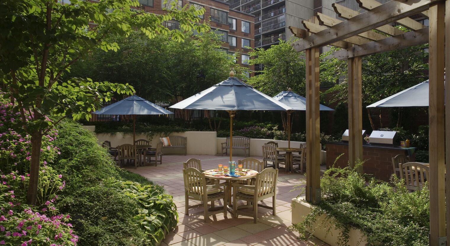 Eine Terrasse mit Sitzgelegenheiten, Sonnenschirmen und einem Grill.