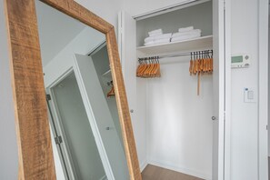 A walk-in closet with shelves, a hanging rack, and a thermostat on the wall. - Blueground | Hell's Kitchen, fitness center, nr Central Park (New York)