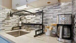 Eine moderne Küche mit einer Edelstahl-Kaffeemaschine, einer integrierten Spüle und einer Spritzschutzwand mit Ziegeloptik.