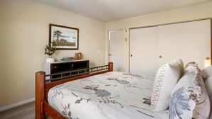 Ein Schlafzimmer mit Bett, Kommode, einem gerahmten Bild an der Wand und einem Kleiderschrank.