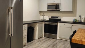 Een moderne keuken met roestvrijstalen apparatuur, witte kasten en een houten vloer.