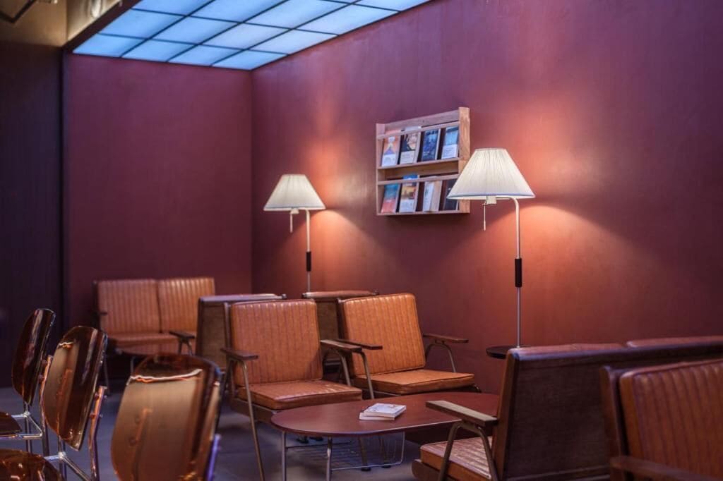 A seating area with cushioned chairs, tables, and two standing lamps.