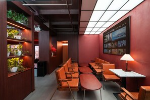 Un interno moderno con mobili in legno, un proiettore e una parete decorata con manifesti cinematografici.