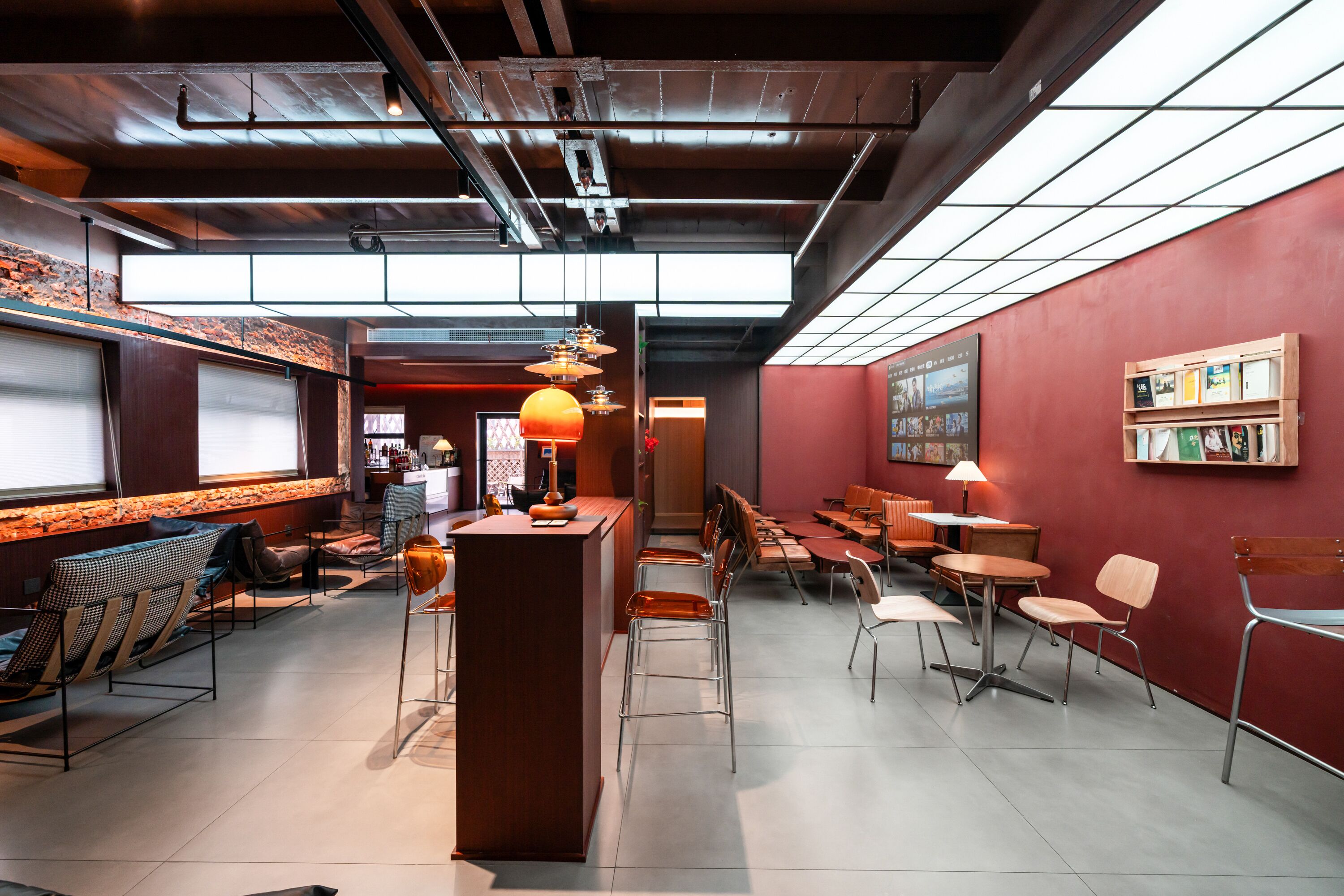 Um interior moderno com área de bar, assentos e uma estante de livros.