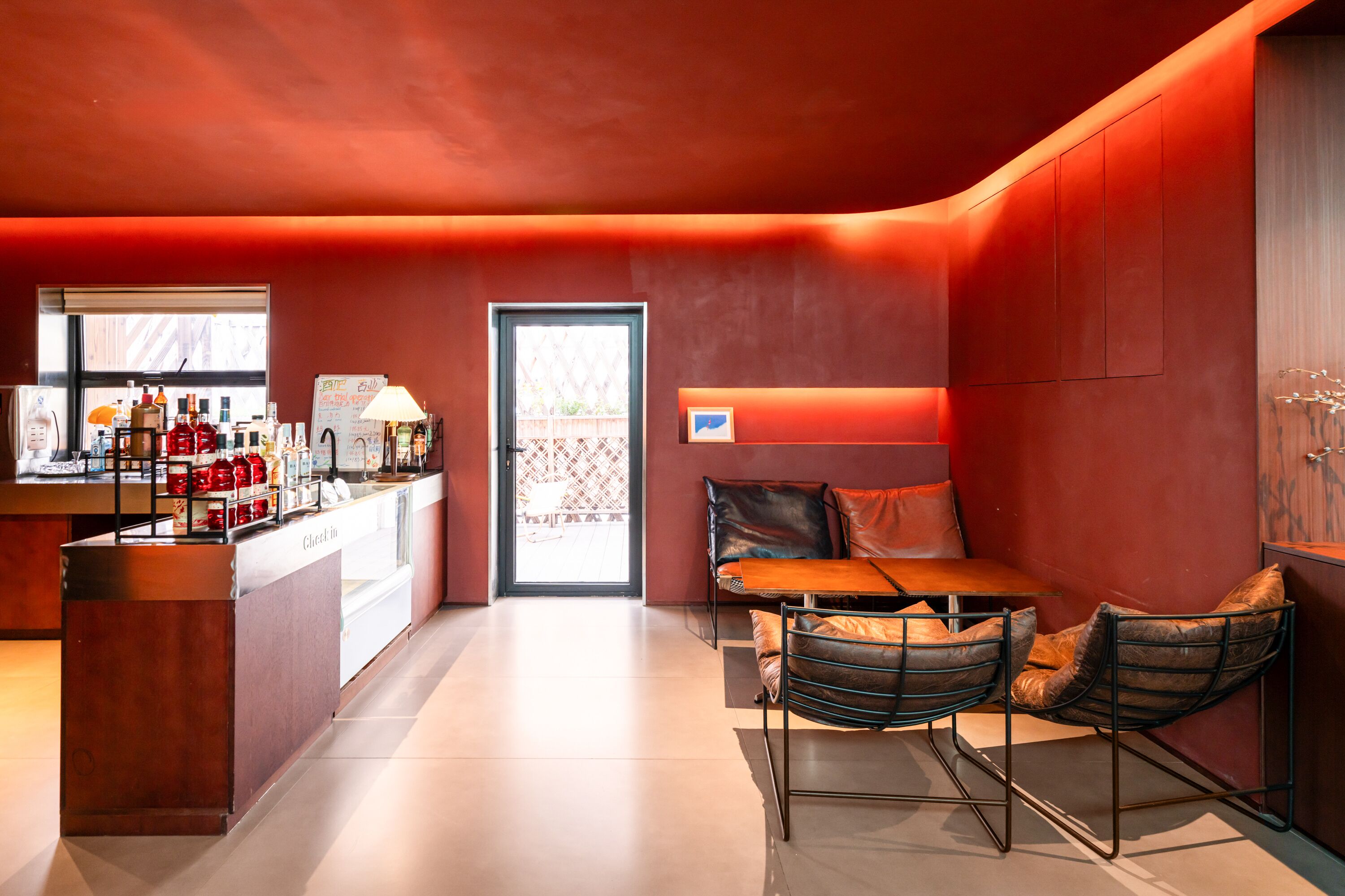 A modern interior with a bar area, seating, and a door leading outside.
