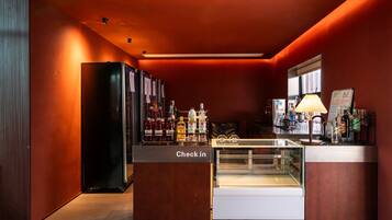 Una zona de bar con una recepción, estantes llenos de botellas de licor y una vitrina de cristal.
