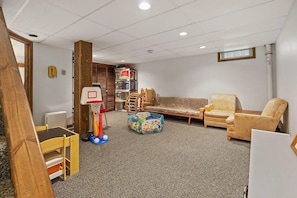 A room with a carpeted floor, a wooden chair, a sofa, a small table, and a toy ball pit. - Charming 3-bedroom house in peaceful Scarborough perfect for relaxing. (Scarborough)