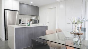 A modern kitchen with a built-in island, stainless steel appliances, and a glass dining table with chairs.