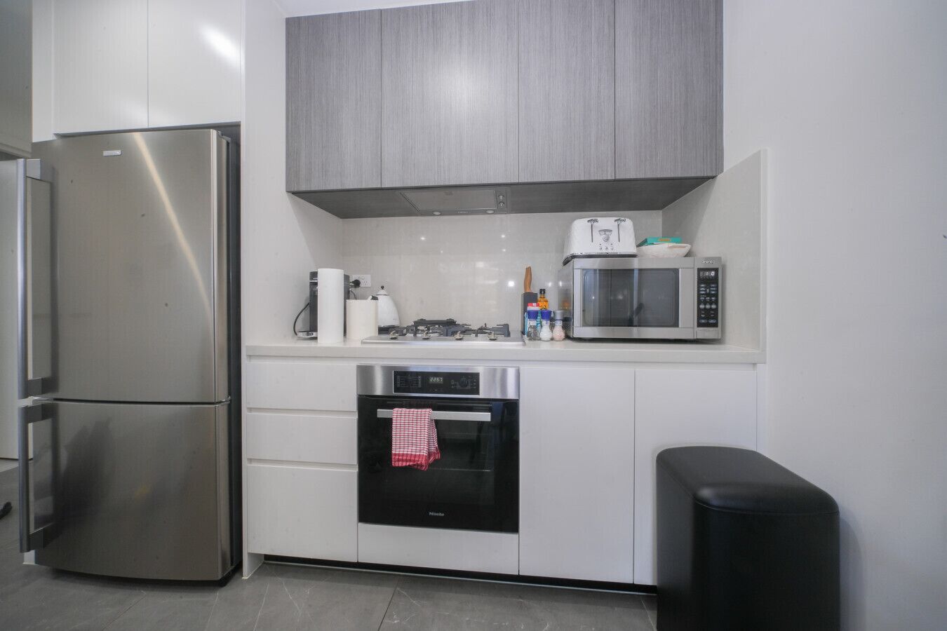 A modern kitchen with a stainless steel refrigerator, a microwave, and an oven.