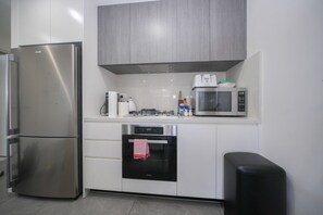 A modern kitchen with a stainless steel refrigerator, a microwave, and an oven.