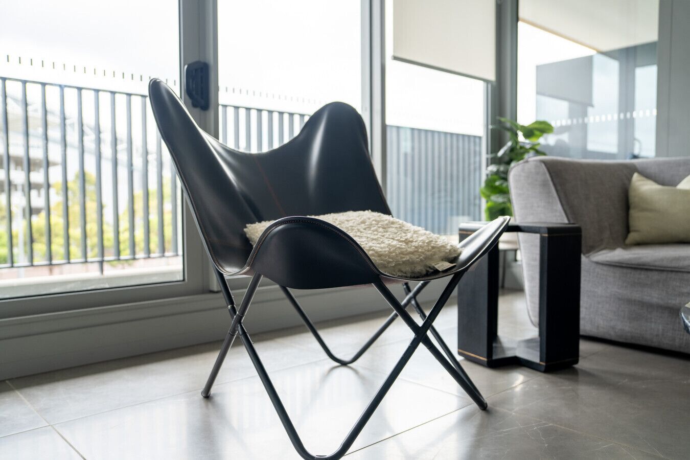 A modern chair with a white cushion, positioned near a window with a view of greenery.
