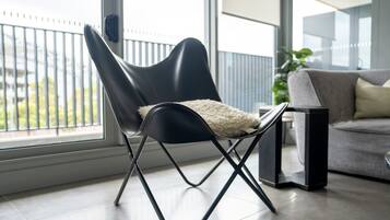 A modern chair with a white cushion, positioned near a window with a view of greenery.
