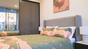 Ein Schlafzimmer mit Bett, Nachttisch, Fenster und Tür.
