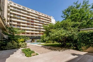 A multi-story residential building with a courtyard featuring a swimming pool, greenery, and a garden area. - PREMIUM 3-BEDROOM APARTMENT IN A PRESTIGIOUS PARIS NEIGHBORHOOD (Paris)