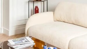 Un saló modern amb un sofà, una taula de centre amb revistes i un plat, una làmpada penjada a la paret i un paper pintat amb dibuixos.