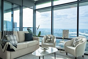A modern living room with a sofa, armchair, and coffee table, large windows with a city view. - Sydney Olympic Park View Bliss | Modern Design (Sydney Olympic Park)