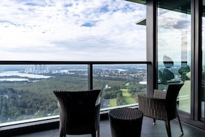 A balcony with wicker chairs and a view of a cityscape and lake.