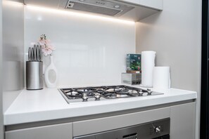 A modern kitchen with a gas stove, stainless steel utensils, a vase with flowers, and a box of Ceylon tea.
