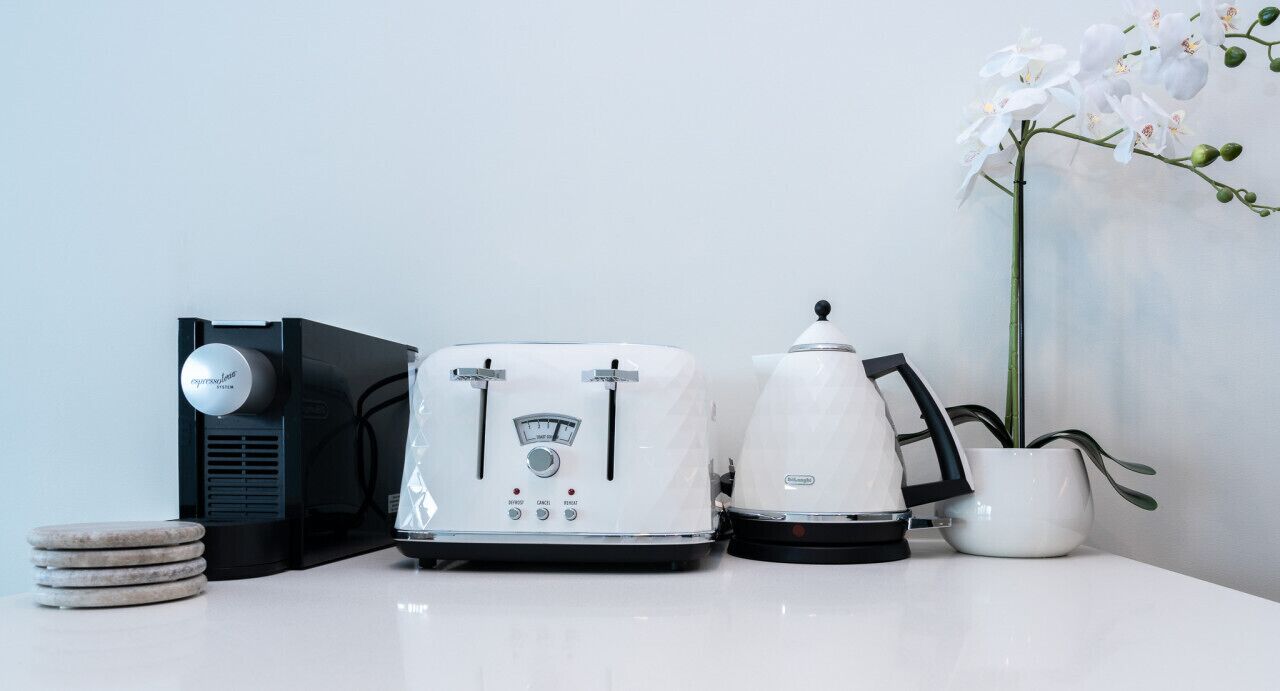 A kitchen counter with a toaster, a coffee maker, and a potted orchid.