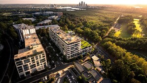 An aerial view of a modern urban area with multiple buildings, roads, and a river. - Sydney Olympic Park View Bliss | Modern Design (Sydney Olympic Park)